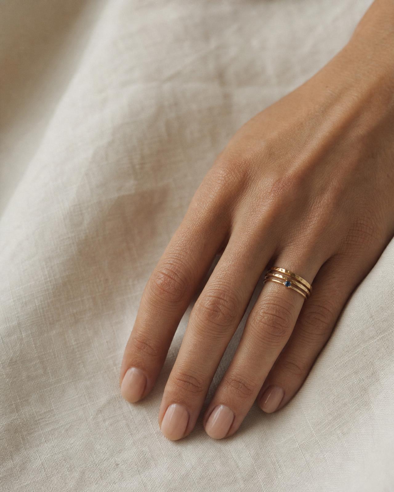 Close-up of a woman's hand wearing an engagement ring stacked with two thin diamond wedding bands